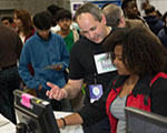 NIGMS Director Dr. Jon R. Lorsch explains a protein letter computer activity to a young participant at the USA Science and Engineering Festival